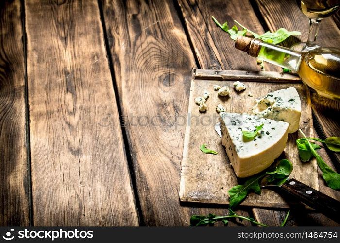 Bottle with white wine and blue cheese on a cutting Board.. Bottle with white wine and blue cheese on cutting Board.