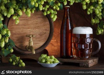 Bottled and unbottled beer with barrel and fresh hops for brewing still-life
