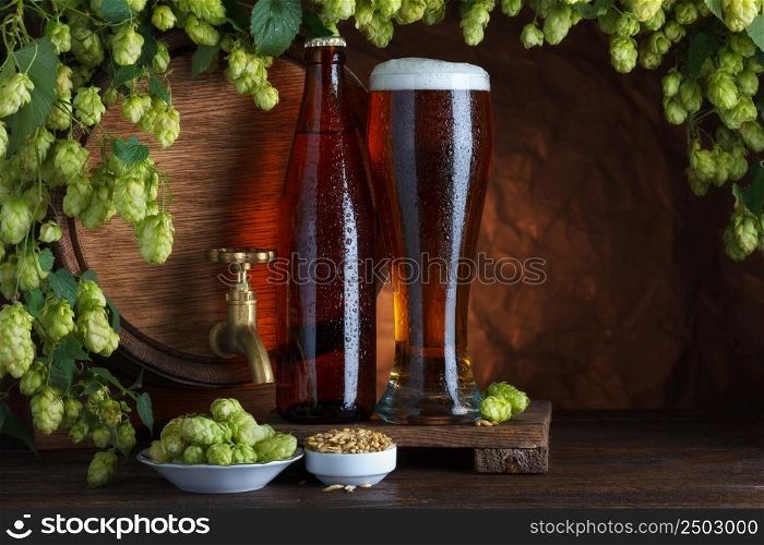 Bottled and unbottled beer with barrel, barley and fresh hops for brewing still-life