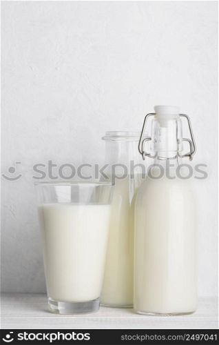 Bottles and glass of milk on white wooden table still life