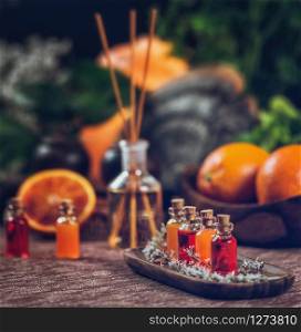 Bottles filled with red and orange essential oils and aromatherapy bottle with wooden sticks inside. Fresh citrus fruit cut in half. Aromatherapy relax concept