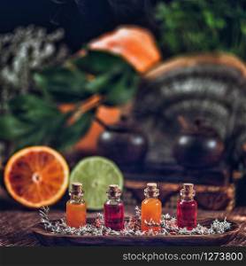 Bottles filled with red and orange essential oils on wooden board. Fresh citrus fruit, orange and lime cut in half. Aromatherapy relax concept