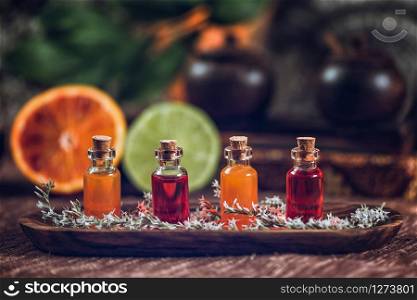 Bottles filled with red and orange essential oils on wooden board. Fresh citrus fruit, orange and lime cut in half. Aromatherapy relax concept