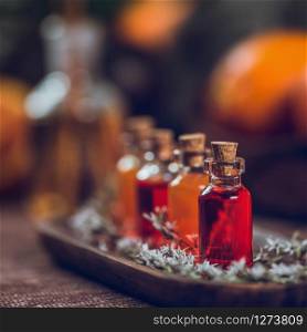 Bottles filled with red and orange essential oils on wooden board. Aromatherapy relax concept