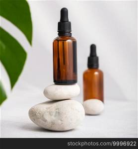Bottles of dark amber glass with essential oil and tropical leaf. Natural organic cosmetic, aromatherapy message oil.