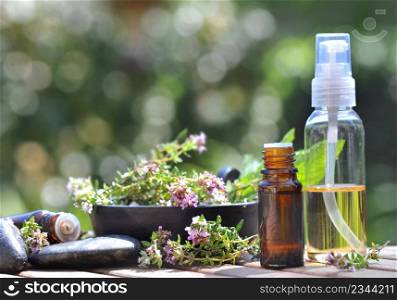 bottles of essential oil and flowers of aromatic herb on a table and on blur lights background. bottles of essential oil and flowers of aromatic herb on a table and on green background