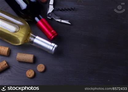 Bottles of red and white wine with corks on dark wooden table. Glass of red wine