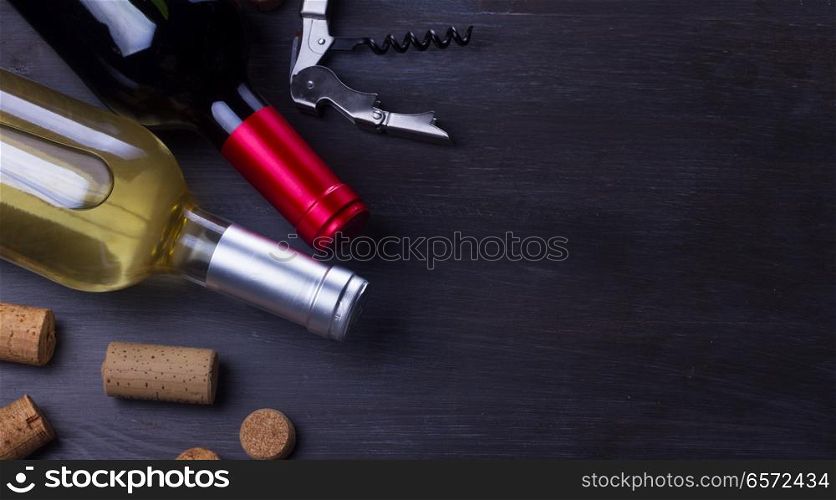 Bottles of red and white wine with corks on dark wooden table. Glass of red wine