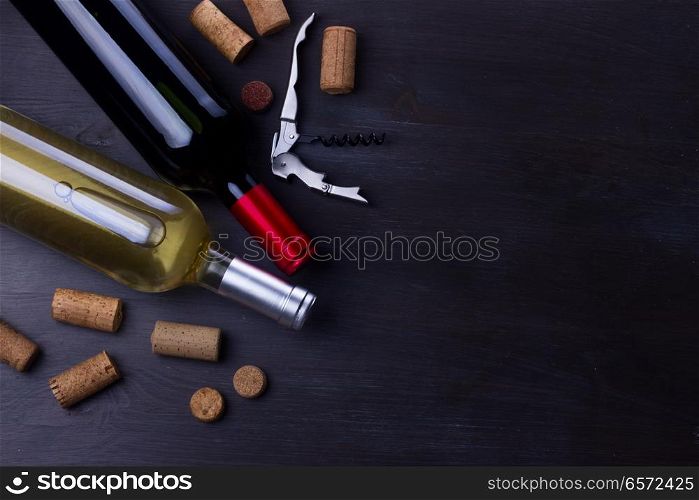 Bottles of red and white wine with corks on table. Glass of red wine