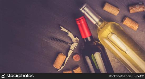 Bottles of red and white wine with corks on wooden tablet, toned image. Glass of red wine