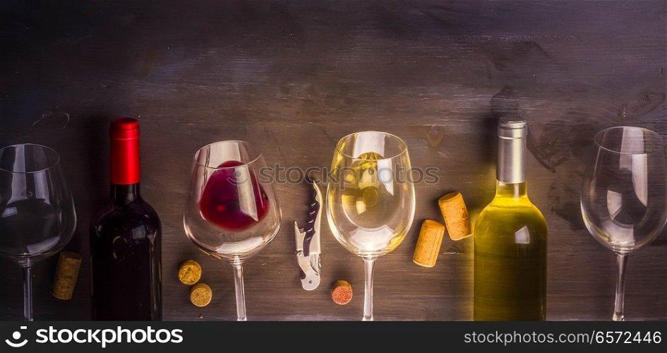 Bottles of red and white wine with wine glasses on table with copy space, toned image. Glass of red wine