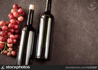 Bottles of red wine with bunch of grapes flat lay
