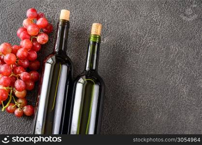 Bottles of red wine with bunch of grapes flat lay