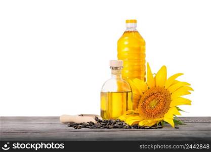 Bottles of sunflower oil with seeds and sunflower on wooden table isolated on white background. Blank for a design project. Bottles of sunflower oil with seeds and sunflower on wooden table isolated on white background