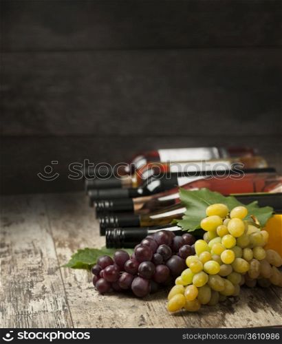 Bottles of wine and grapes on wooden background