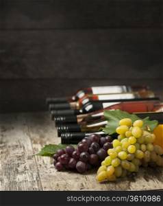 Bottles of wine and grapes on wooden background