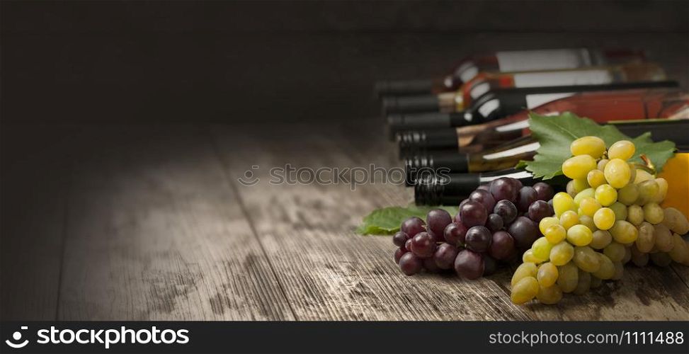 Bottles of wine and grapes on wooden background with copy space
