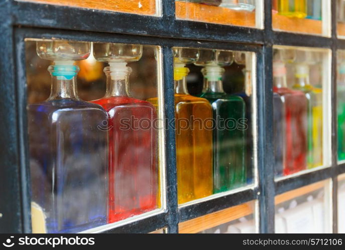 Bottles with colored liquid on the window behind the glass