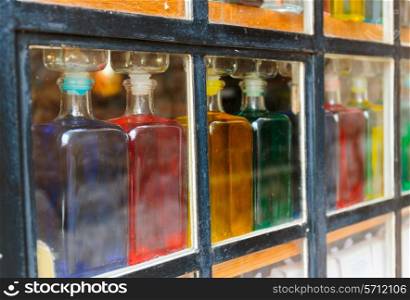 Bottles with colored liquid on the window behind the glass
