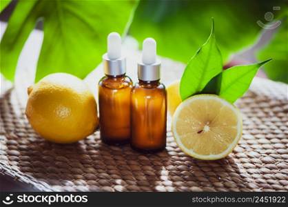 Bottles with lemon oil, fresh fruit whole and half on a natural tropical background.