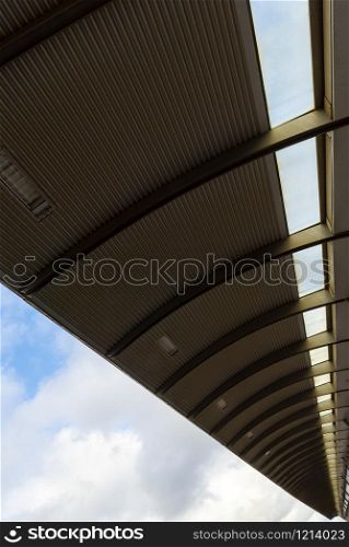 Bottom view of a metal roof from a train station platform. Steel roof construction under the blue sky