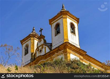 Bottom view of antique and historic church in 18th century colonial architecture on top of the hill in the city of Ouro Preto in Minas Gerais, Brazil with the mountains behind. Bottom view of antique and historic church in 18th century colonial architecture