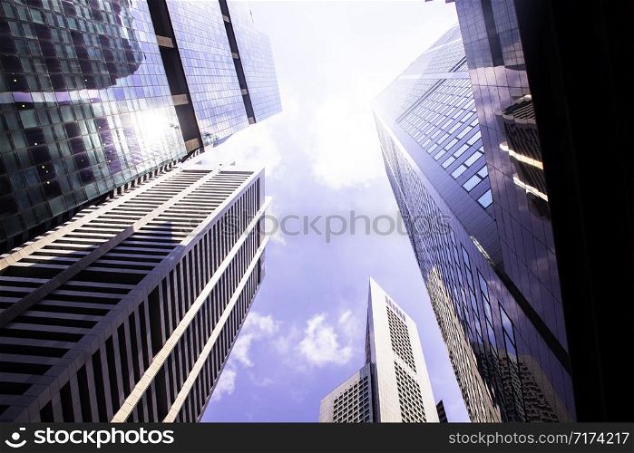 Bottom view of modern skyscrapers/office buildings in the business district of Singapore cities against the blue sky. Economy, finances, business activity concept.