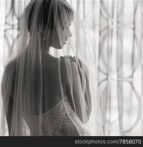 Boudoir, attractive young woman wearing lingerie and she stands front of the window - black and white image