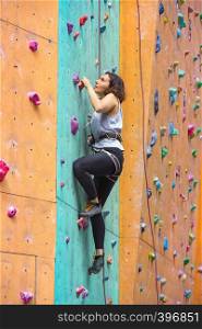 bouldering, beautiful girl climbing up the wall