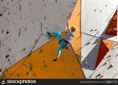 bouldering, girl climbing up the wall