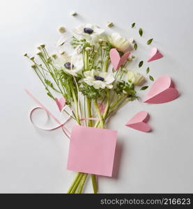 bouquet and card for your text, pink hearts made of paper on a white background. Bouquet of flowers and hearts