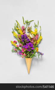 Bouquet field colored flowers in waffle ice cream cone on grey paper background Flat Lay Top view Mock up Concept Women's day or Mothers Day, Hello summer. Bouquet field colored flowers in waffle ice cream cone on grey paper background Flat Lay Top view Mock up Concept Women's day or Mothers Day