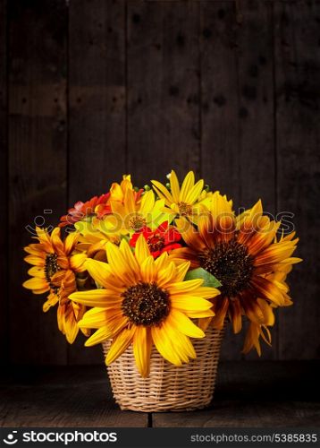Bouquet from sunflowers in basket on the table over wooden background