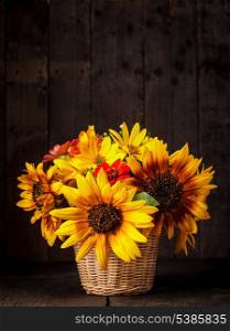Bouquet from sunflowers in basket on the table over wooden background