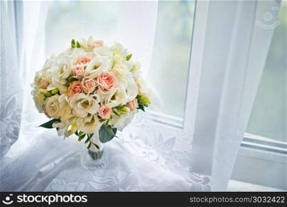 Bouquet lying in curtains on a window sill.. Bouquet for the bride.