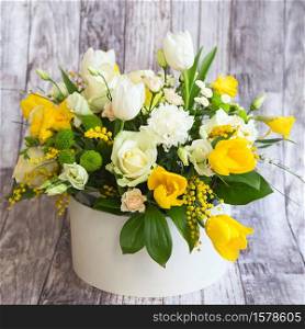 Bouquet of beautiful flowers with white peonies, roses, eustomas and yellow tulips, mimosa with green leaves in the papper gift box on the grey background. Spring medley bouquet. Valentine&rsquo;s Day. Happy Mother&rsquo;s Day card