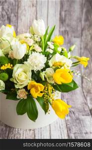 Bouquet of beautiful flowers with white peonies, roses, eustomas and yellow tulips, mimosa with green leaves in the papper gift box. Spring medley bouquet. Valentine&rsquo;s Day. Happy Mother&rsquo;s Day