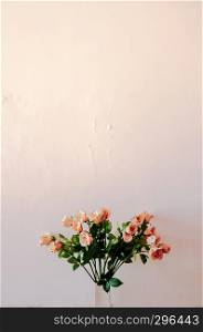 Bouquet of beautiful peach roses in ceramic vase with old rustic light colour wall, vintage rose Bouquet.