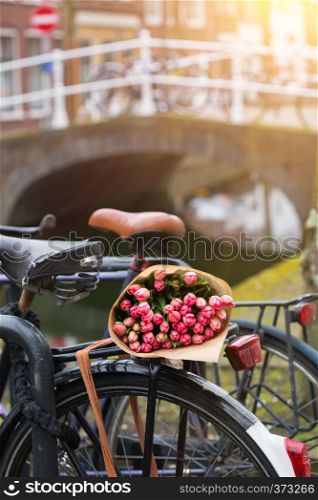 bouquet of beautiful pink tulips lie on the trunk of the bike. Amsterdam