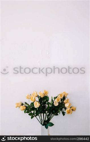 Bouquet of beautiful yellow roses in ceramic vase with old light colour wall, vintage rose Bouquet.