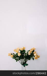 Bouquet of beautiful yellow roses in ceramic vase with old light colour wall, vintage rose Bouquet.