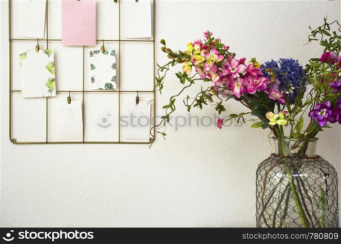 Bouquet of colorful flowers white wall and post cards hanging, modern interior retro. Bouquet of colorful flowers white wall and post cards hanging, modern interior