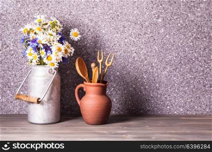 Bouquet of daisies in a vintage tin can and rough ceramic jug with wooden cooking utensil set. The rustic decor