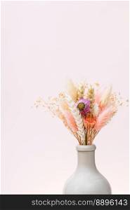 bouquet of dried flowers and spikelets in ceramic bottle on light pink background with copyspace