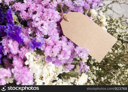 Bouquet of dried flowers with blank paper tag on the wooden table