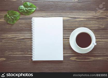 Bouquet of flower and empty diary notebook and a cup of coffee on rustic wooden table with copy space, mockup template with flower and note, top view, vintage retro style.
