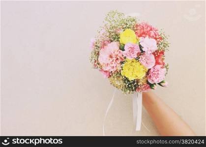 Bouquet of flower in hand and white wall with retro filter effect