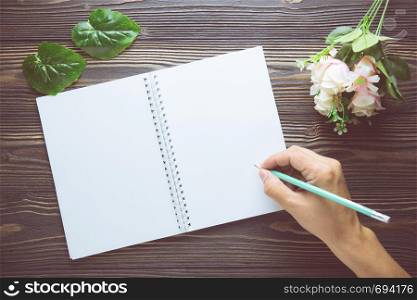 Bouquet of flower with hand writing on empty diary notebook rustic wooden table with copy space, mockup template with flower and note, top view, vintage retro style.