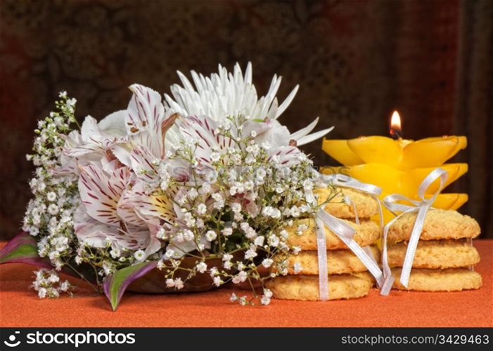 Bouquet of flowers and cookies on an orange background