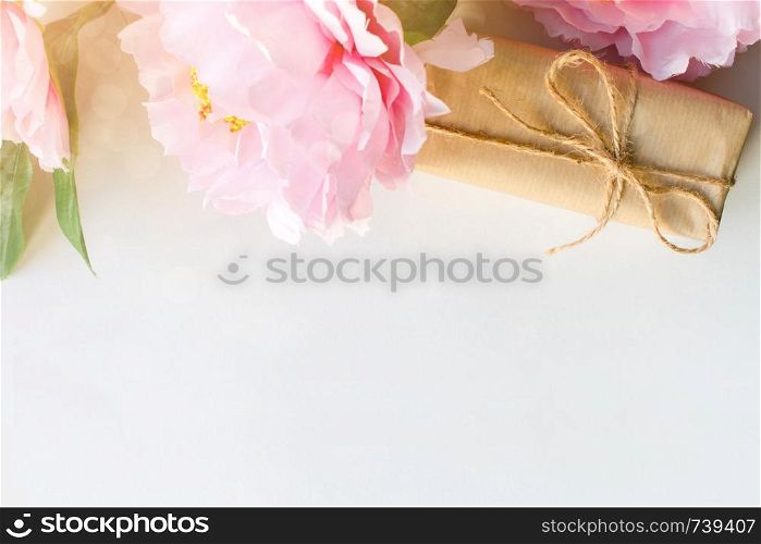 Bouquet of flowers and gift box wrapped with craft paper on white background with copy space for text. Greeting concept. Flat lay. Top view. Bouquet of flowers, gift box wrapped with craft paper on white background. Greeting concept. Copyspace